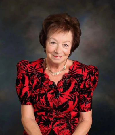 Elderly woman in a red patterned dress smiling.