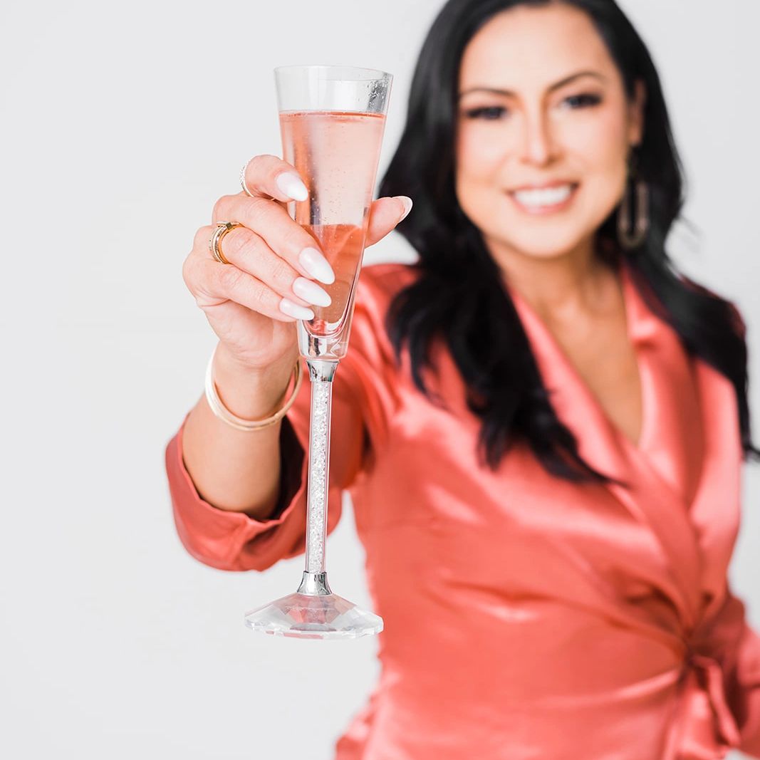 Woman in coral satin dress holding a champagne flute.