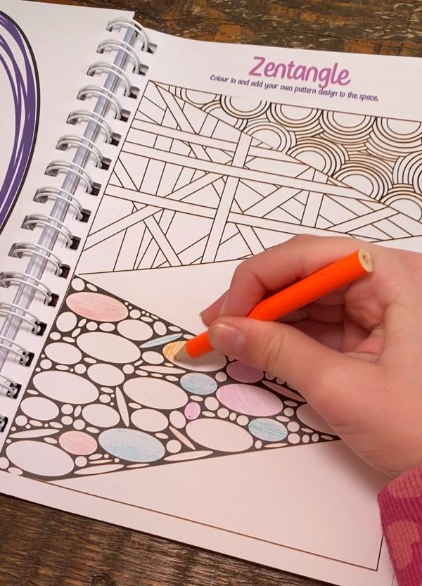 Image showing a child's hand colouring in one of the pages of the journal