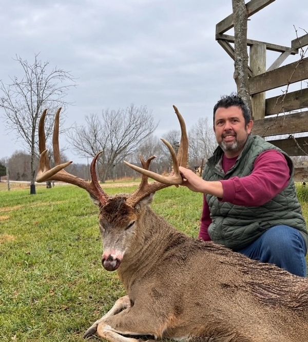 Man posing with large deer on grass.