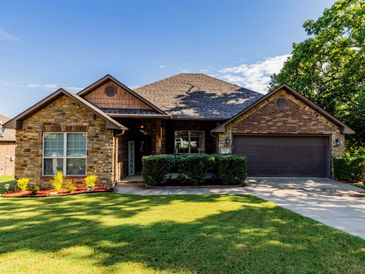 A brick house with a green lawn and driveway.