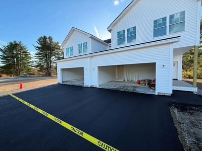 Newly paved driveway with caution tape in front of a two-car garage.