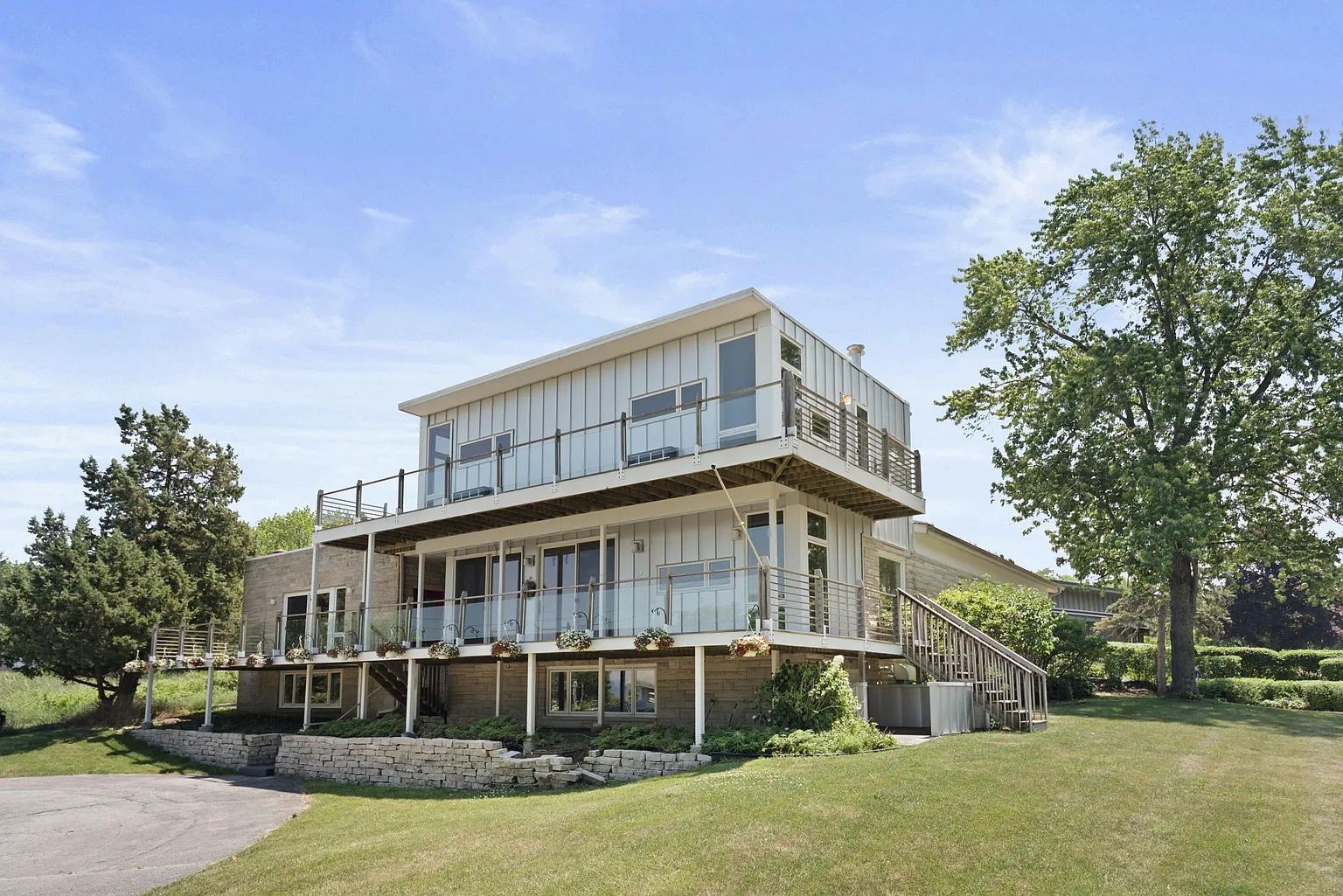 Modern two-story house with large balconies and lush green surroundings.