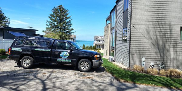 Black pickup truck parked by a gray house with ocean view in background.