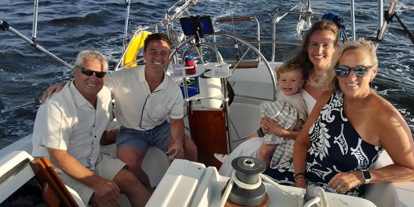 A family sitting comfortably in the cockpit of a sailboat during a peaceful Charlotte Harbor cruise 
