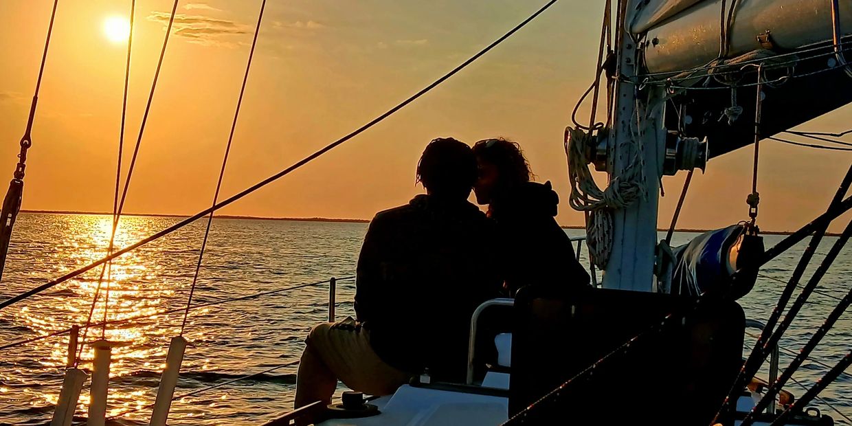 Two people sharing a romantic moment on a sailboat at sunset during a serene Charlotte Harbor cruise