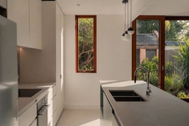 Modern kitchen with white cabinets and large windows.