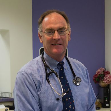 Smiling male doctor with stethoscope in office.