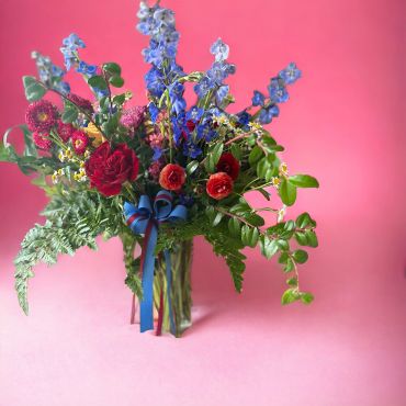 Colorful flower bouquet with red, blue, and pink blooms against a pink background.