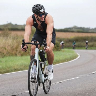 Cyclist with a prosthetic leg racing on a country road during a cycling event.