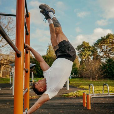 Man performing a human flag exercise on outdoor gym bars.