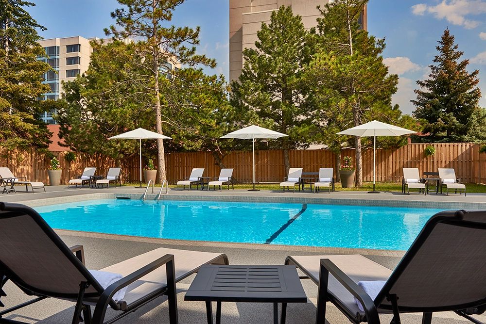 Outdoor pool area with lounge chairs and umbrellas in a sunny setting.