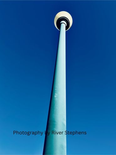 Tall street lamp against a bright blue sky.