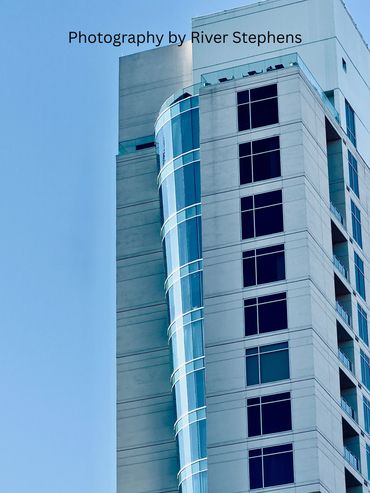 Modern high-rise building with reflective glass windows against a clear sky.