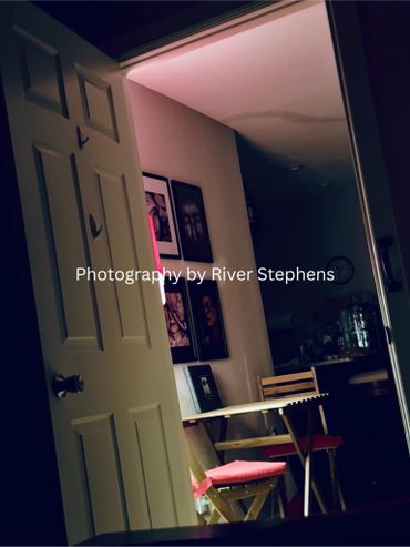 Dimly lit room with chairs and framed pictures on the wall.