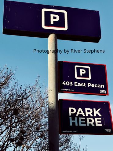 Parking signs indicating a parking area at 403 East Pecan.