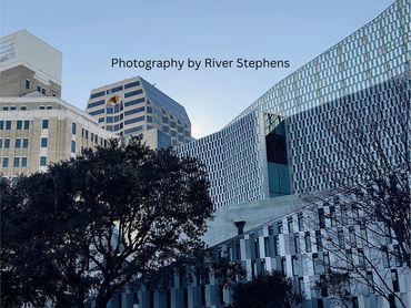 Modern cityscape with unique architectural building and trees under clear sky.