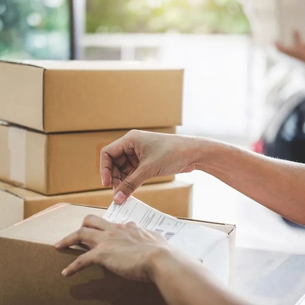 Person attaching a shipping label to a cardboard box.