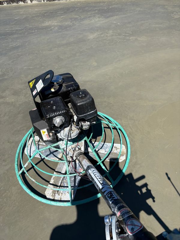 A power trowel smoothing concrete for a hard trowel finish. Have a concrete project? reach out and get a free estimate!