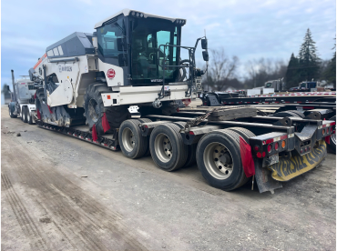 Heavy machinery loaded on a flatbed truck on a road.