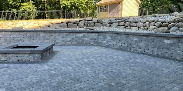 Outdoor stone patio with built-in fire pit and retaining walls.