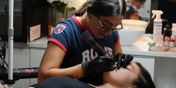 Tattoo artist working on a client's lips.