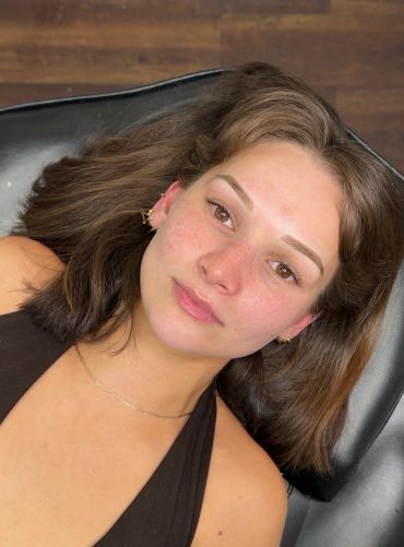 Young woman lying down on a black surface.