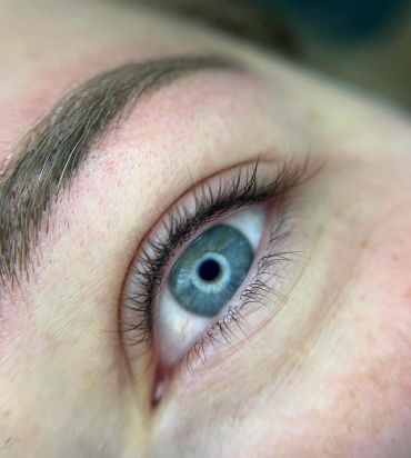 Close-up of a blue eye with detailed eyelashes and eyebrow.