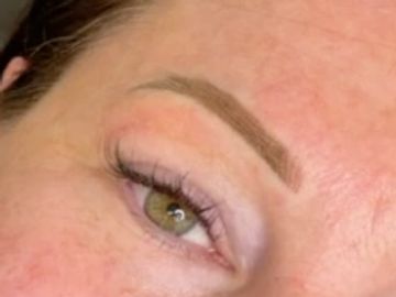 Close-up of a green eye with well-groomed eyebrow and long eyelashes.