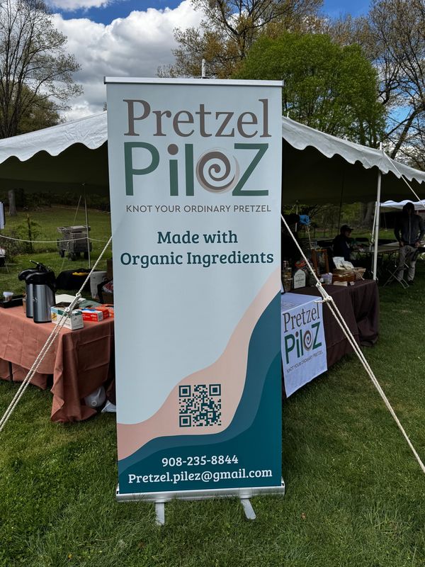 Pretzel Pilez banner promoting organic pretzels at an outdoor market.