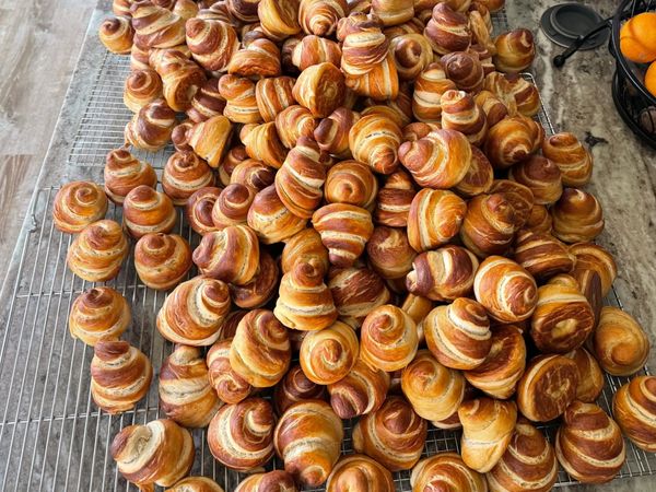 A large pile of freshly baked, golden-brown croissants cooling on wire racks.