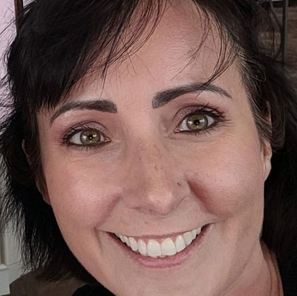 Close-up portrait of a smiling woman with dark hair and green eyes.