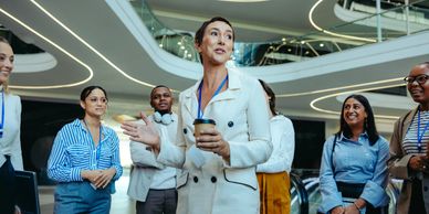 Confident businesswoman speaking to a diverse group in a modern office.