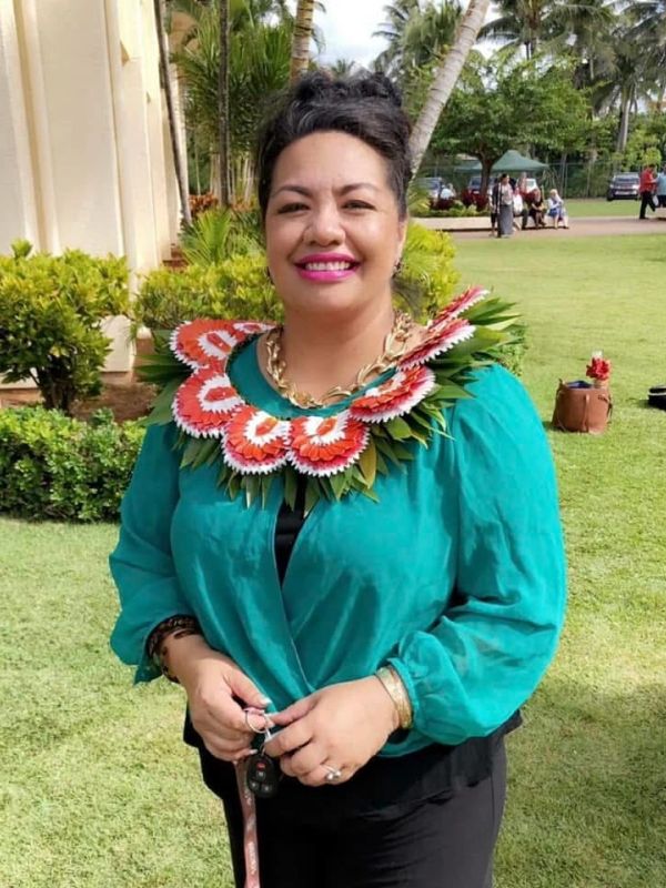 Smiling woman wearing a traditional floral necklace.