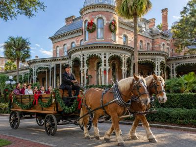 Horse-drawn carriage with people in front of a decorated historic building.
