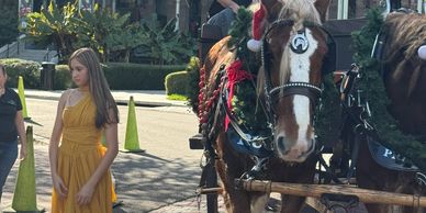 A girl in a yellow dress standing near a decorated horse.