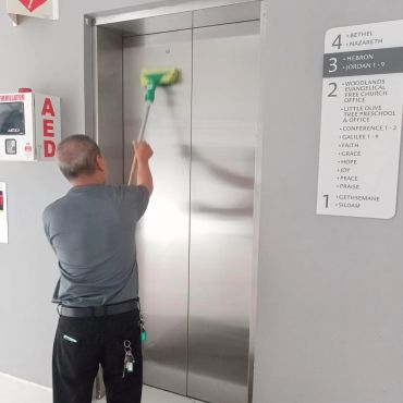 Man cleaning elevator doors with a squeegee.