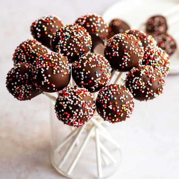 Chocolate cake pops with colorful sprinkles arranged in a glass.