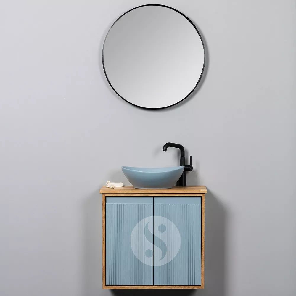 Modern bathroom sink with blue cabinet and round mirror.