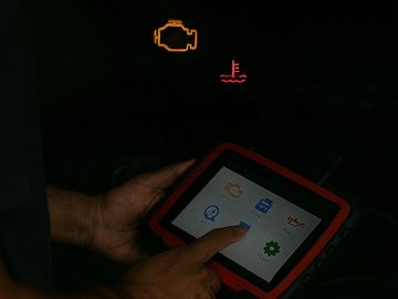 Person using a diagnostic tool on a car with warning lights on.