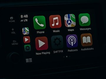 Car infotainment system displaying various app icons and time.