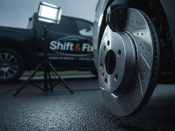 Close-up of a brake rotor being replaced on a vehicle at a repair shop.