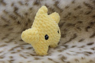 A yellow plush star with black eyes on a furry surface.