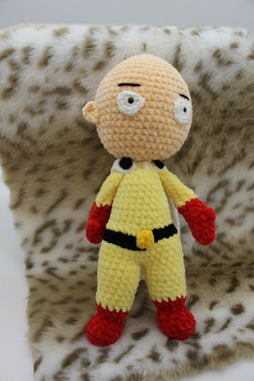 Crocheted doll of a superhero character with a bald head.