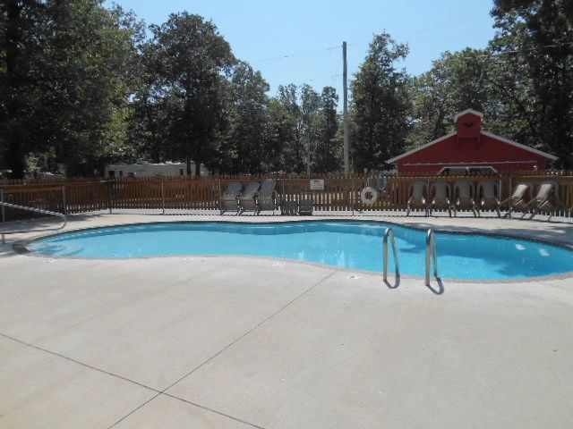 Empty outdoor pool with chairs and a red shed in the background.