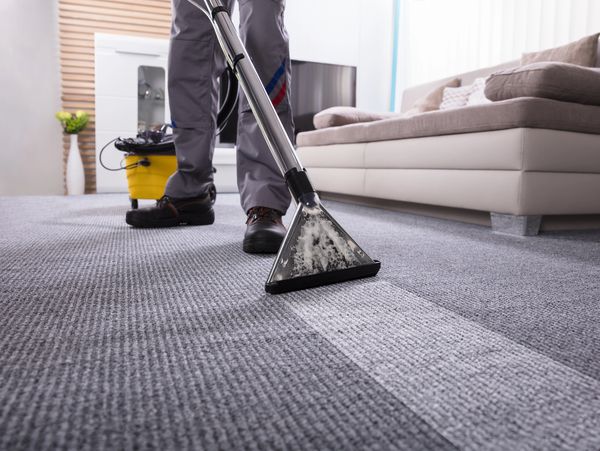 Person Cleaning The Carpet With Vacuum Cleaner In Living Room