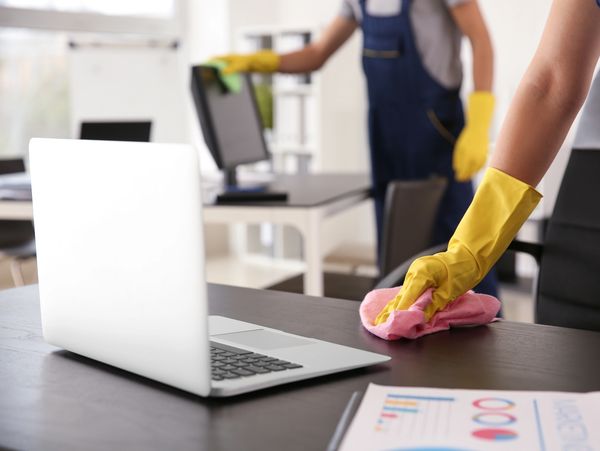 Janitor wiping table in office