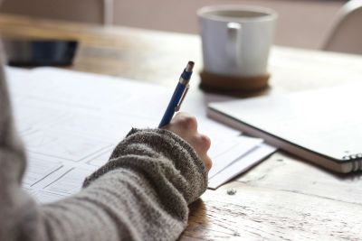Person writing on paper with a pen.