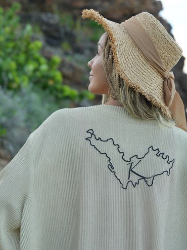 Woman wearing a hat and light sweater outdoors.