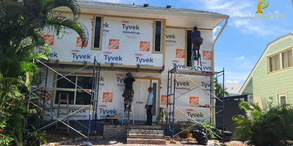 Workers installing Tyvek HomeWrap on a house exterior under construction.